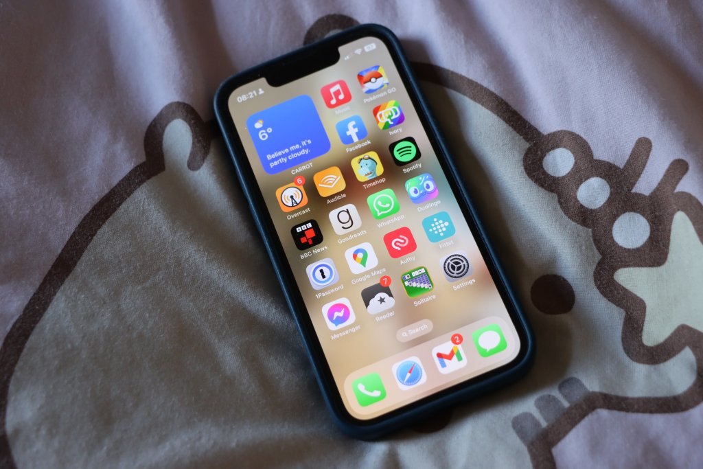 A photo of an iPhone 13 Mini with iOS 15 showing the home screen