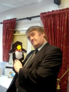 A photo of Dave Jennings at our wedding, holding a Mr Flibble penguin puppet