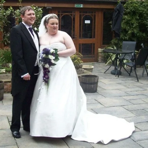 A photo of Neil and Christine at their wedding. Neil is wearing a morning suit, and Christine is wearing a big wedding dress and holding a bouquet