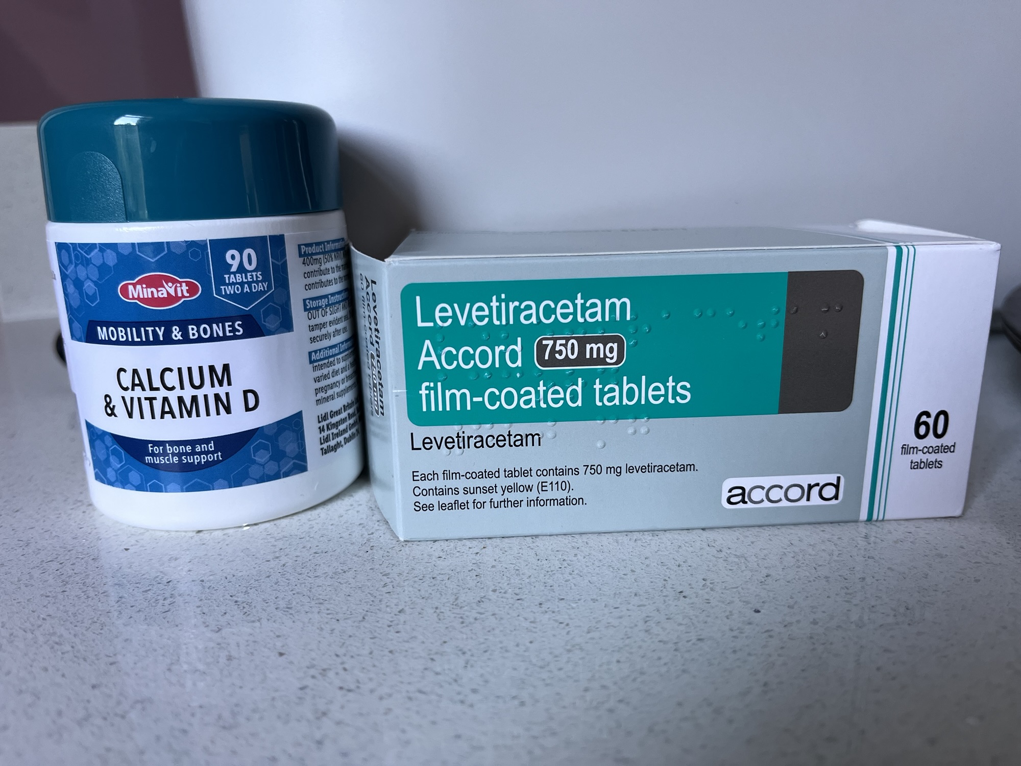 A photo of a jar of calcium and vitamin D supplements, and a box of Levetiracetam tablets